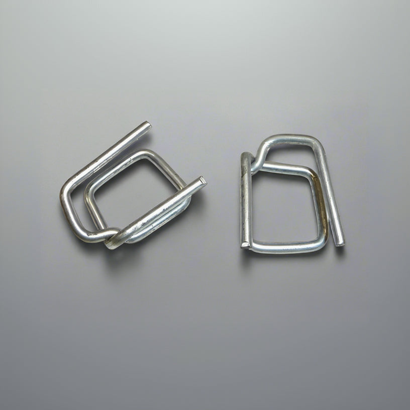Two silver wire buckles for PP strapping, designed for securing loads, placed on a grey background. Two silver wire buckles for PP strapping, designed for securing loads, placed on a grey background.